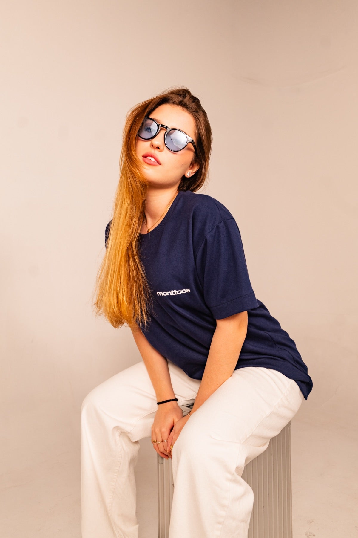 Mulher sentada, de camiseta azul MONTTCO e óculos escuros